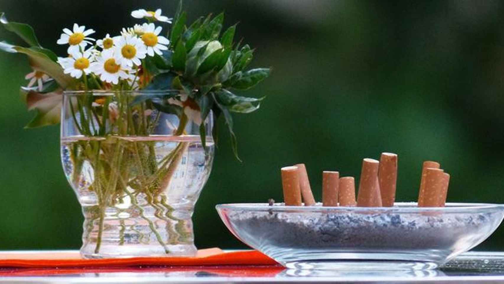 Un cenicero con varias colillas apagadas junto a un ramo de flores silvestres: los fumadores españoles lo están dejando