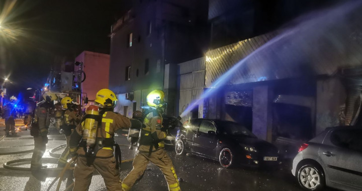 Bomberos durante las labores de extinción del incendio en la nave ocupada de Badalona / BOMBERS