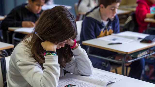 Una estudiante hinca los codos en el pupitre de clase