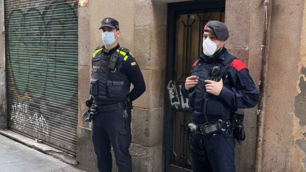 Un agente de la Guardia Urbana y otro de los Mossos d'Esquadra durante el operativo en un narcopiso del Raval / MOSSOS