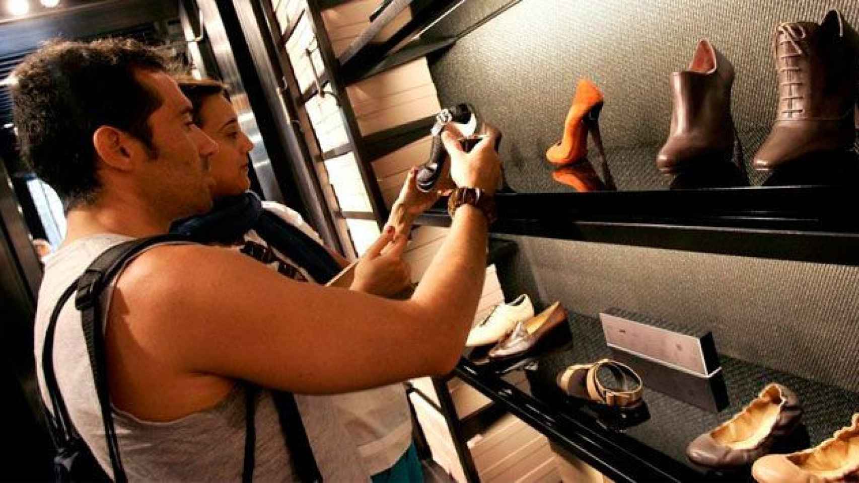 Una pareja mira zapatos en un comercio de Barcelona. Calzado / CG