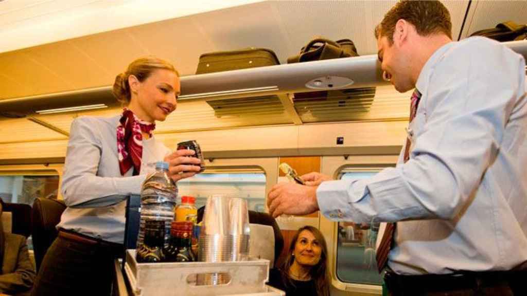 Dos trabajadores de a bordo del AVE de Renfe, sirviendo comida a una pasajera / CG