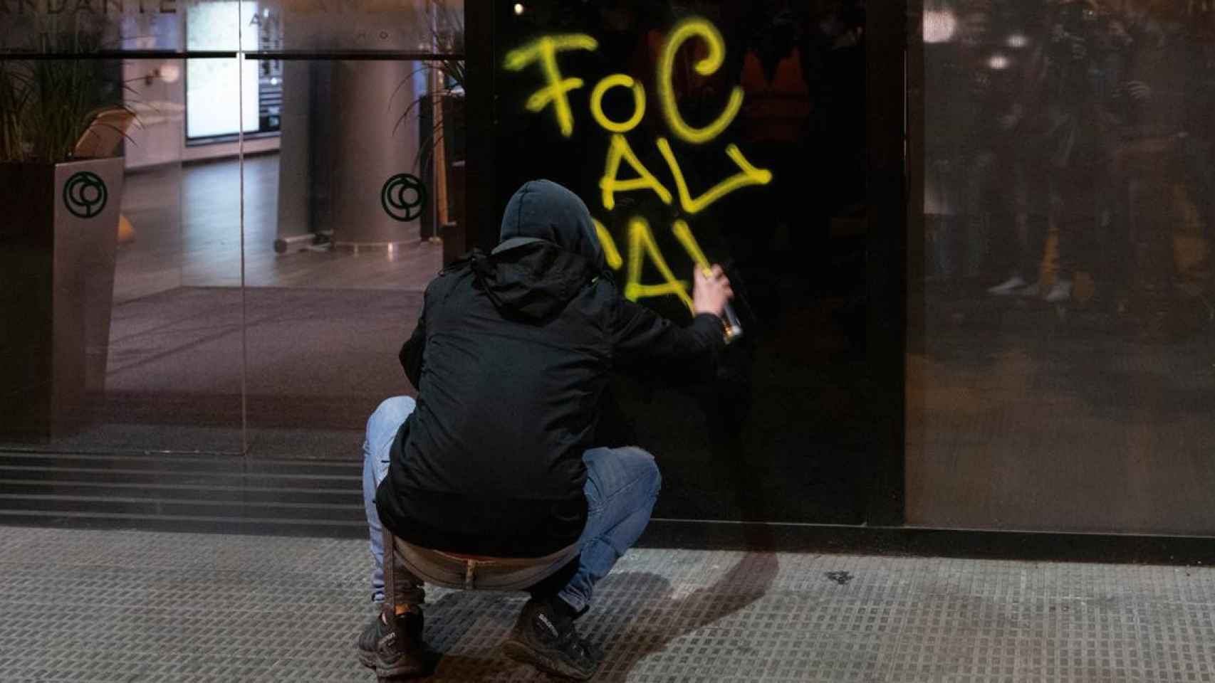 Imagen de un manifestante pintando una entidad bancaria / EP