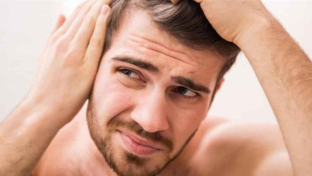 Un hombre comprueba su cabello