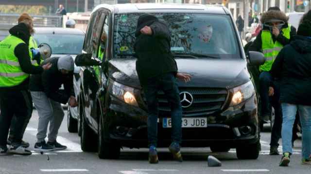 Taxistas de Barcelona atacando un vehículo VTC, como los que utilizan Uber y Cabify, ayer / EFE