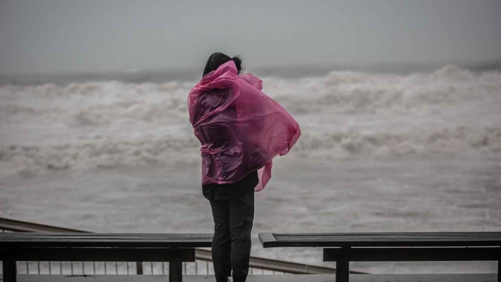 Una mujer contempla desde el paseo marítimo de Barcelona en un temporal