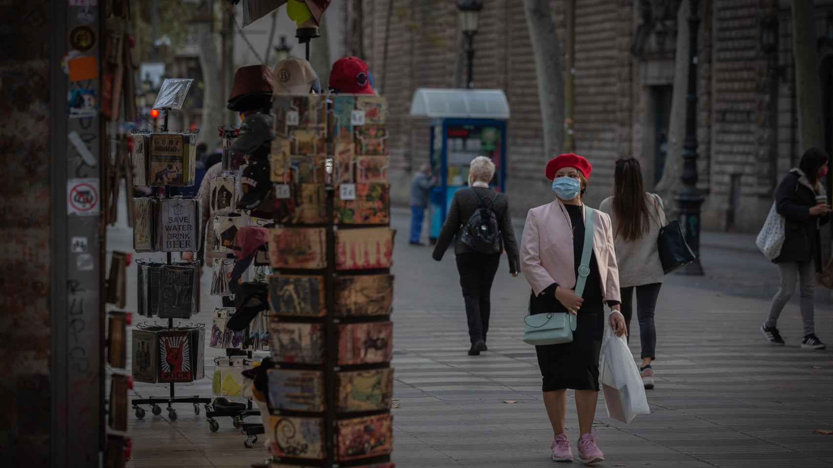 Una mujer frente a una tienda de artículos turísticos en una Barcelona vacía por el Covid / EP