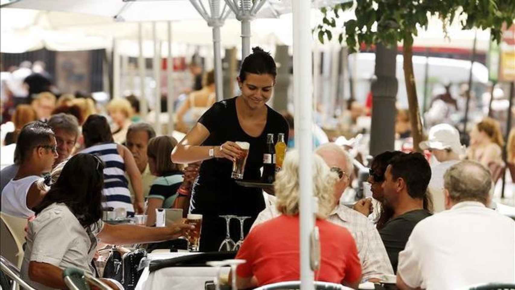 Una camarera sirve a unos turistas en la terraza de un restaurante / EFE