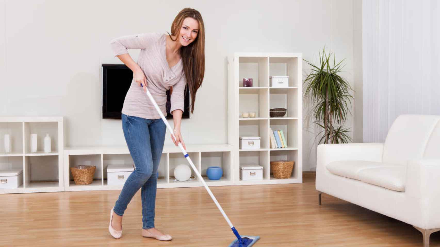 Una mujer pasando el mocho por su casa