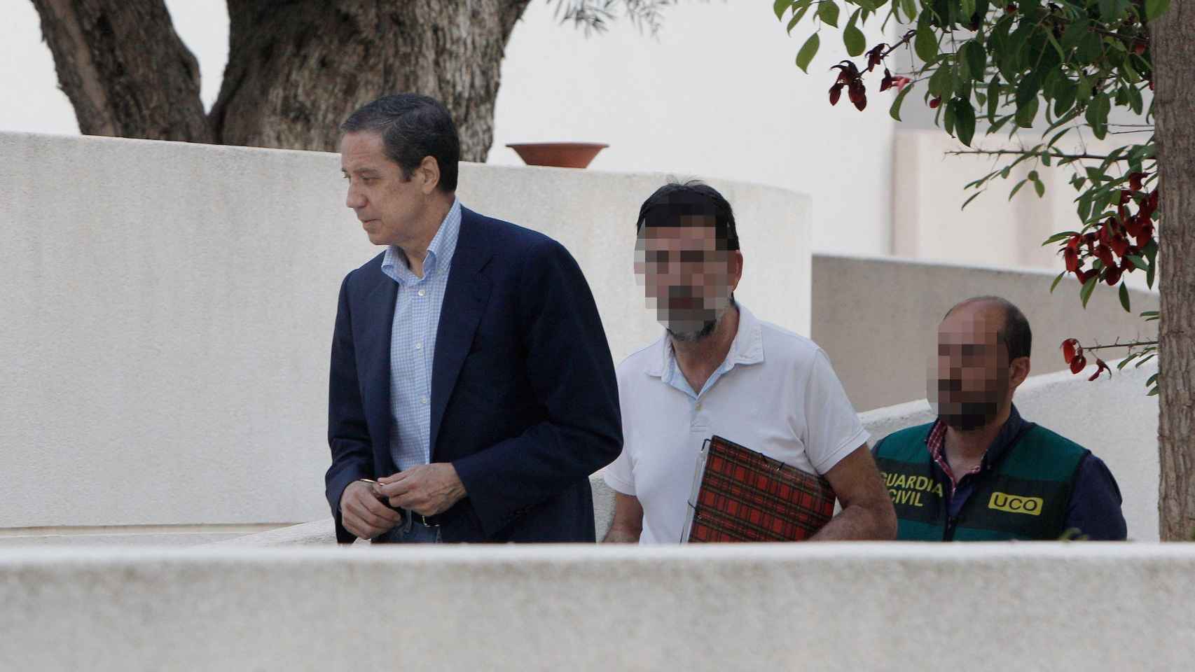 Eduardo Zaplana acompaña a dos policías durante el registro de su chalé de Benidorm esta tarde / EFE