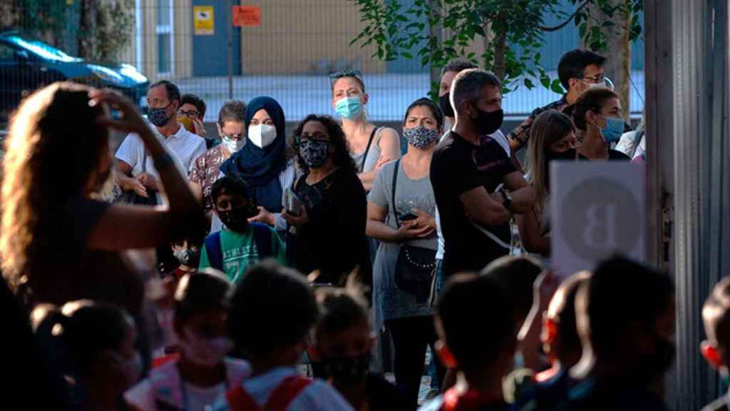 Padres y alumnos esperan a las puertas de un colegio en Barcelona durante un día del curso escolar 2020-2021. Castellano / EP