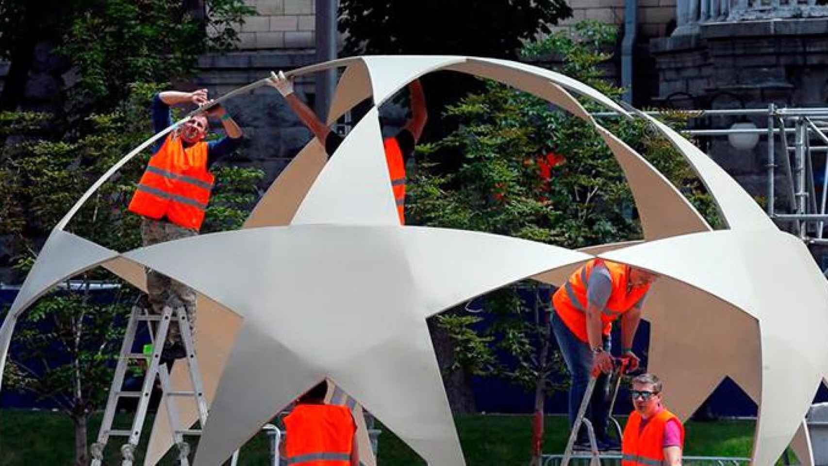 Trabajadores construyen una estructura decorativa que representa al balón de la Champions en la zona para fans habilitada en el centro de Kiev con motivo de la final de la Liga de Campeones / EFE