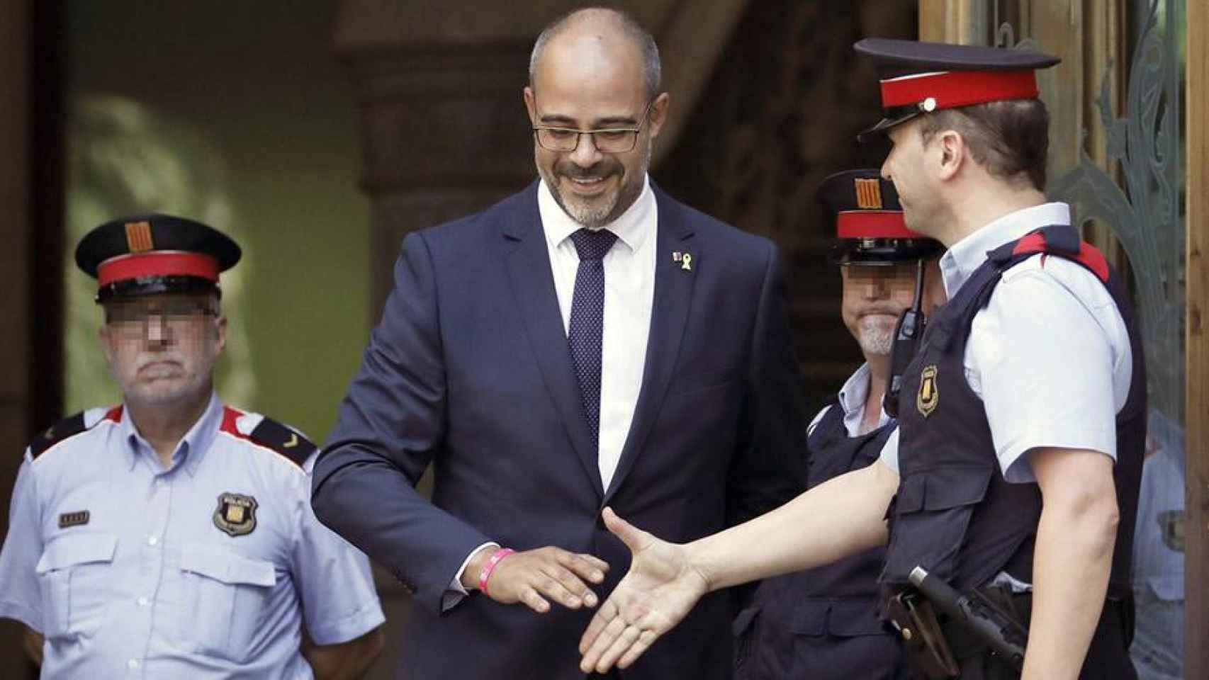 El consejero de Interior, Miquel Buch, quien ha encargado una investigación en los Mossos por las cargas policiales, saluda a un agente a la salida del Tribunal Superior de Justicia de Cataluña / EFE