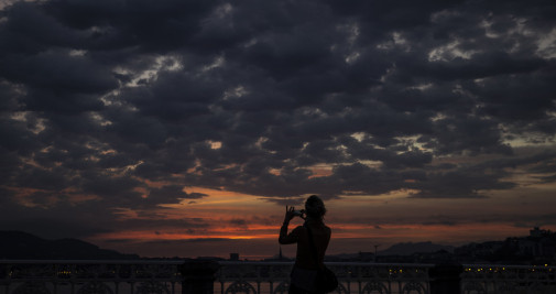 Una mujer fotografiando San Sebastián, donde se prevén chubascos / EFE