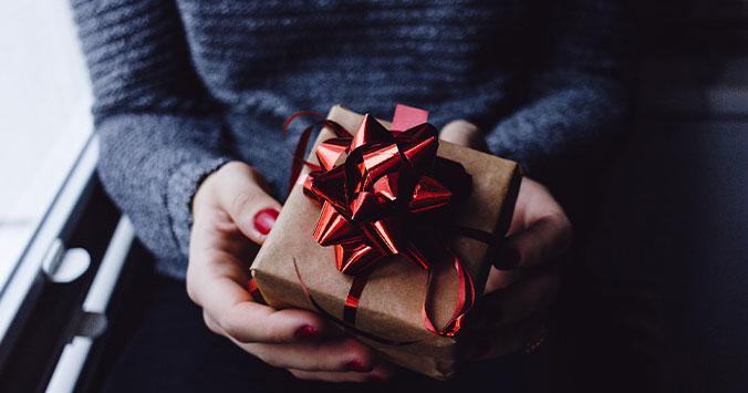 Persona sujetando uno de los regalos comprados para la Navidad / UNSPLASH