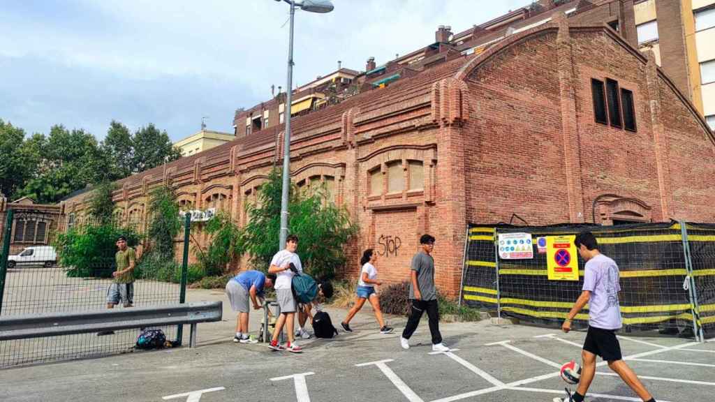 Un grupo de niños jugando ante la antigua fábrica que acogerá el polémico Tanatorio de Sants / CG