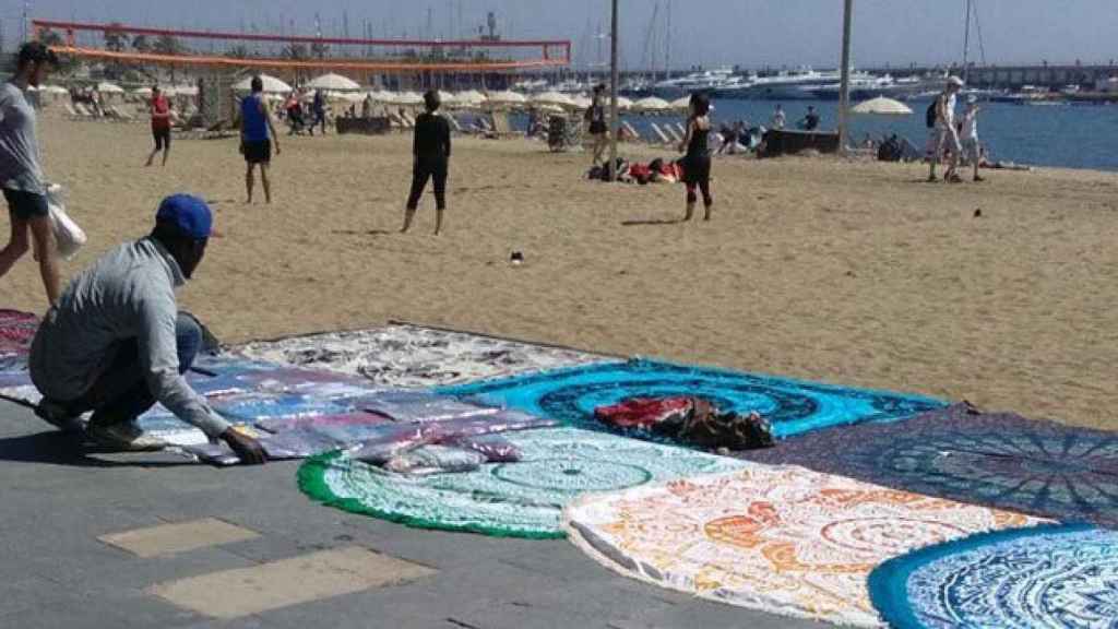 Un 'mantero' vende pareos en la playa de la Barceloneta / AC