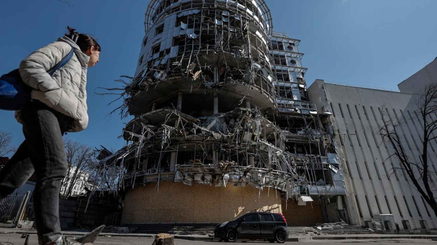 Una mujer camina ante un edificio seriamente dañado por los bombardeos que sufre la ciudad de Jarkiv, en el punto de mira de Moscú / MANUEL BRUQUE - EFE