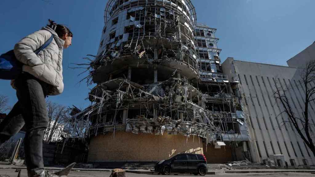 Una mujer camina ante un edificio seriamente dañado por los bombardeos que sufre la ciudad de Jarkiv, en el punto de mira de Moscú / MANUEL BRUQUE - EFE