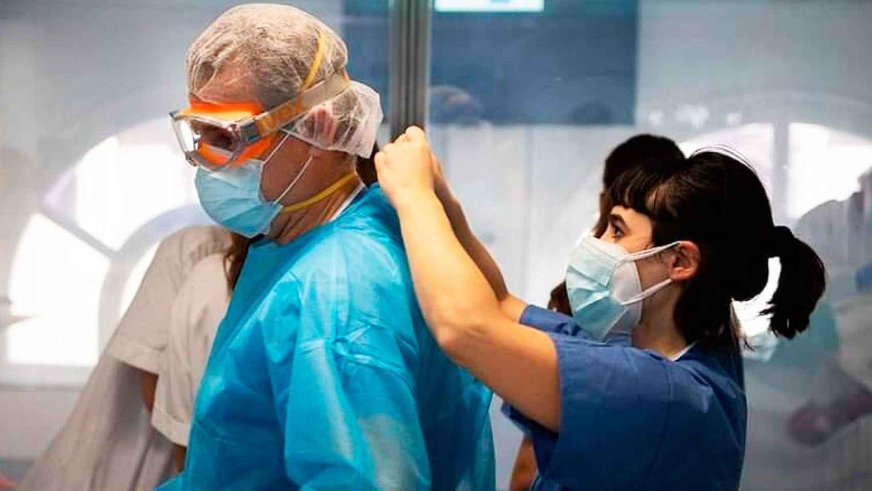 Una sanitaria del Hospital Clínic Barcelona, vistiendo a un compañero / CG