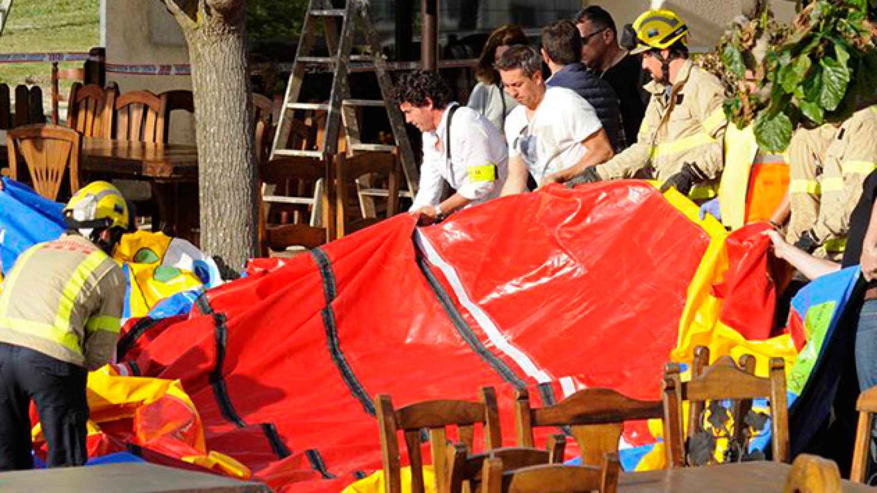 Varios operarios y bomberos retiran el castillo hinchable del restaurante Mas Oller, de Caldes de Malavella / CG