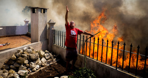 n vecino pide agua sobre las llamas que avanzan hacia su casa durante el incendio forestal en Canecas, a las afueras de Lisboa, Portugal / EFE