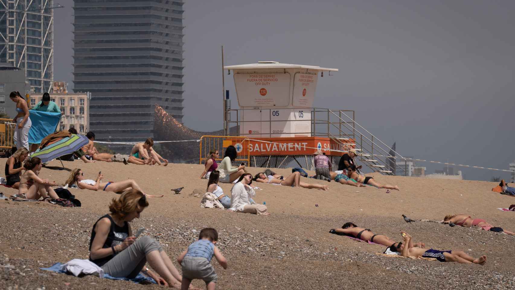 Varias personas toman el sol en la playa de la Barceloneta