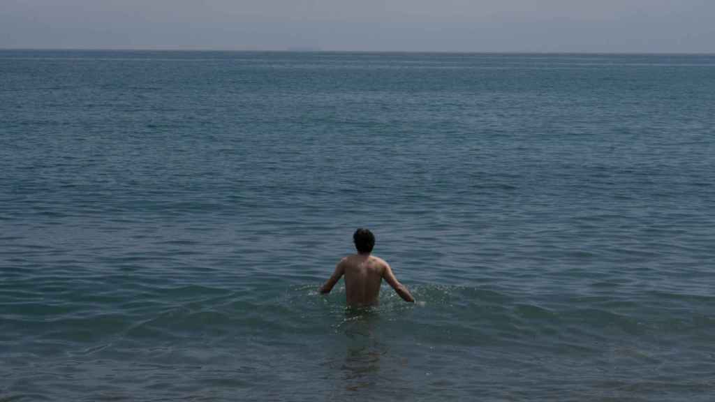 Un hombre se da un baño en la playa de la Barceloneta