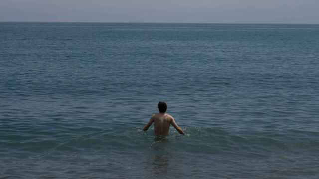 Un hombre se da un baño en la playa de la Barceloneta