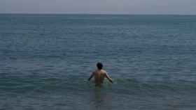 Un hombre se da un baño en la playa de la Barceloneta