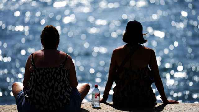 Dos personas observan el mar en la playa de la Barceloneta de Barcelona este lunes en plena ola de calor intenso en Cataluña