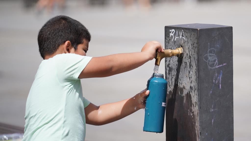 Un niño se aprovisiona de agua por el calor