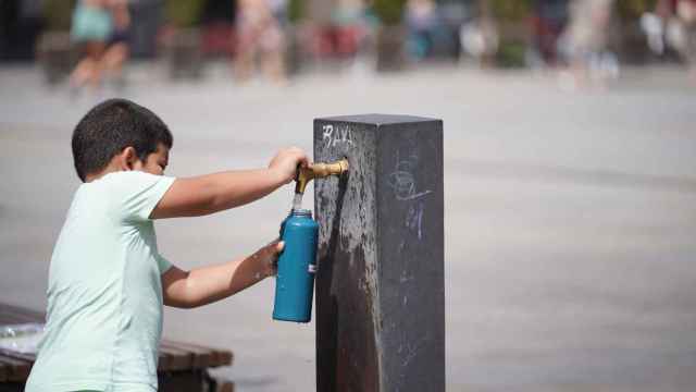 Un niño se aprovisiona de agua en una fuente en plena ola de calor