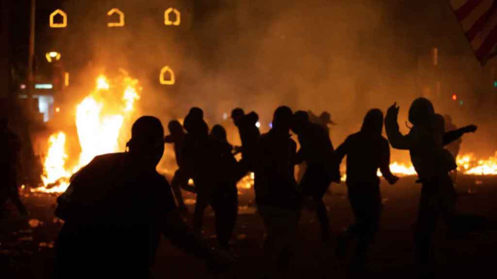 Manifestantes frente al fuego durante los disturbios en la plaza de Urquinaona, en Barcelona a 18 de octubre de 2019