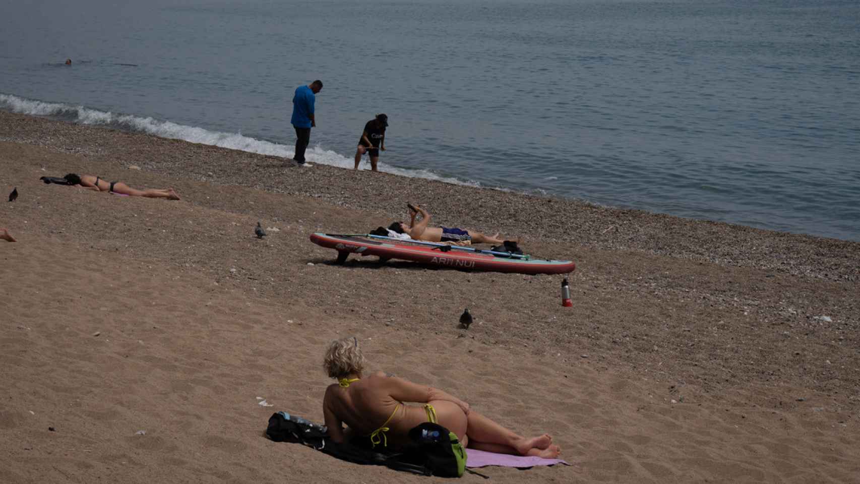 Varias personas toman el sol en la playa de la Barceloneta