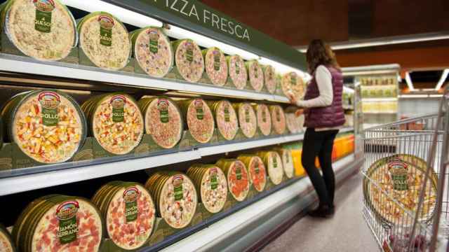 Imagen de archivo de una mujer comprando en la sección de pizzas de un supermercado