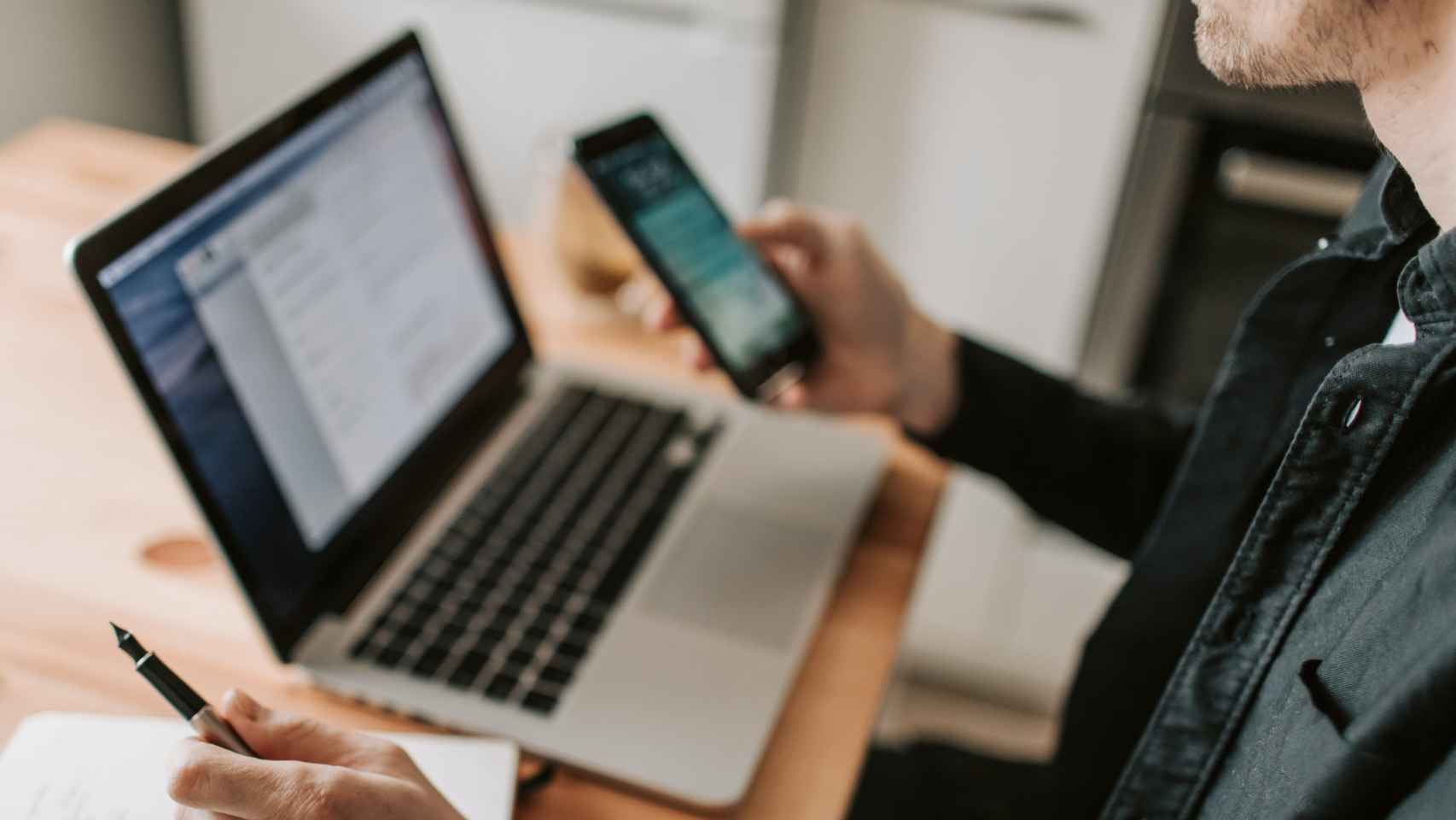 Un hombre utilizando un ordenador y un teléfono móvil