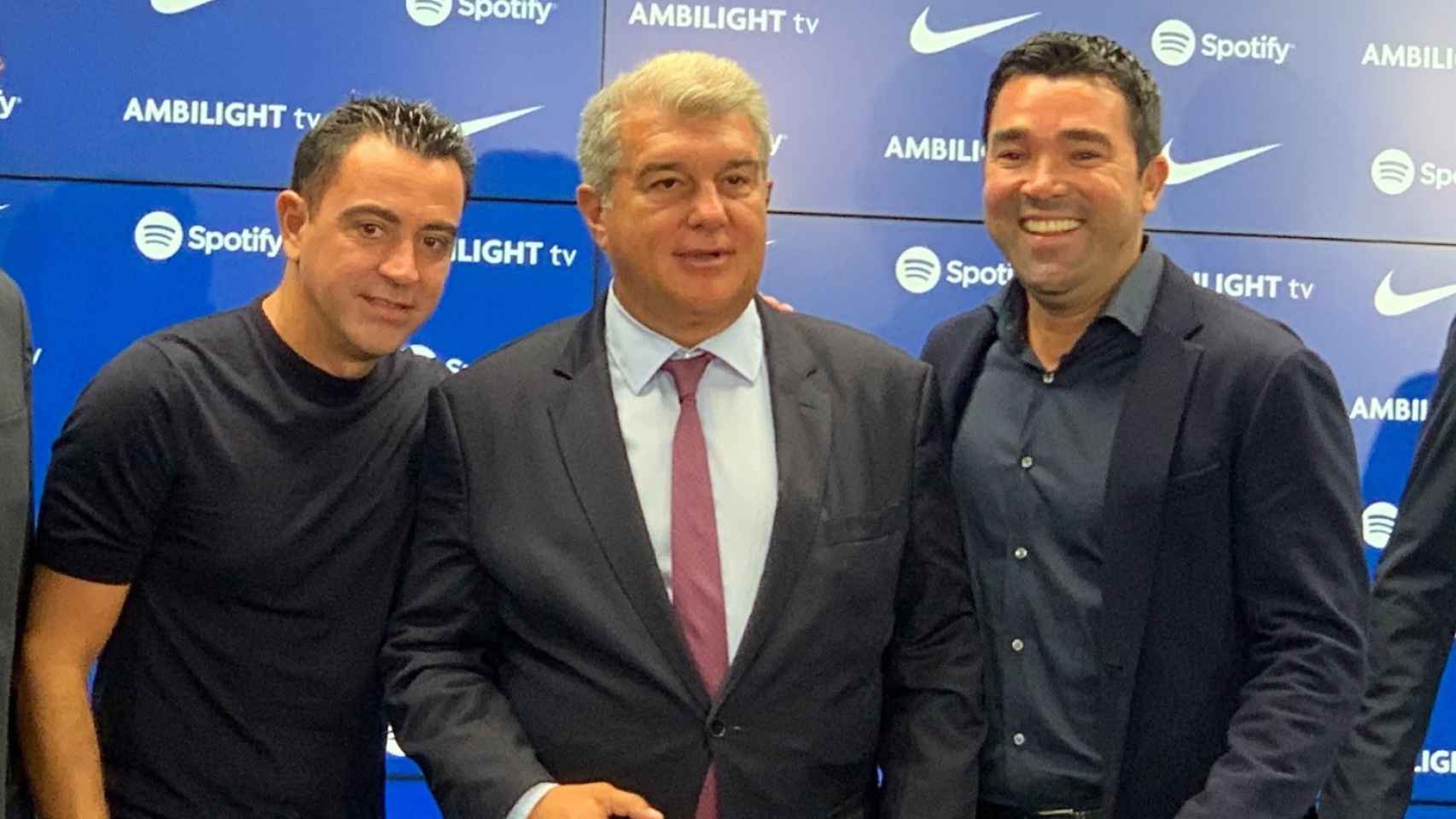 Xavi y Deco sonríen posando junto al presidente Laporta