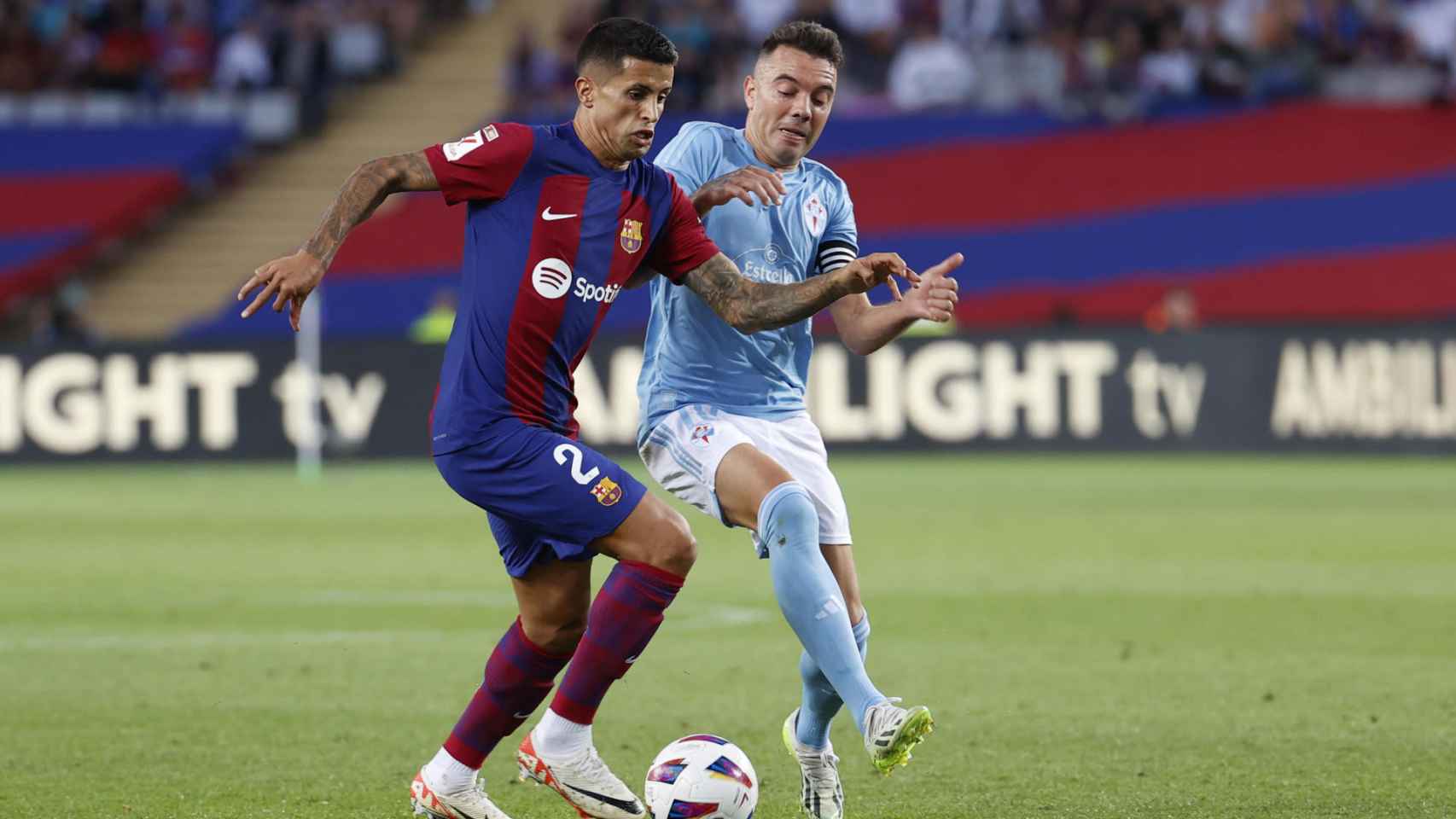 Joao Cancelo conduce un balón, presionado por Iago Aspas