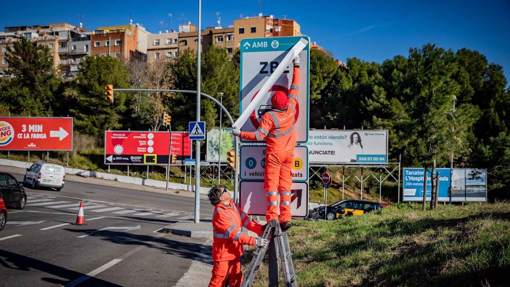 Dos operarios, colocando paneles de la ZBE en Barcelona