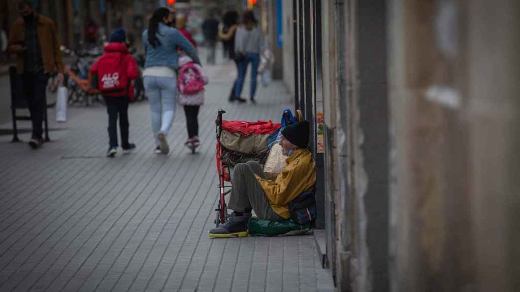 Una persona sin techo permanece en el suelo de una calle de Barcelona