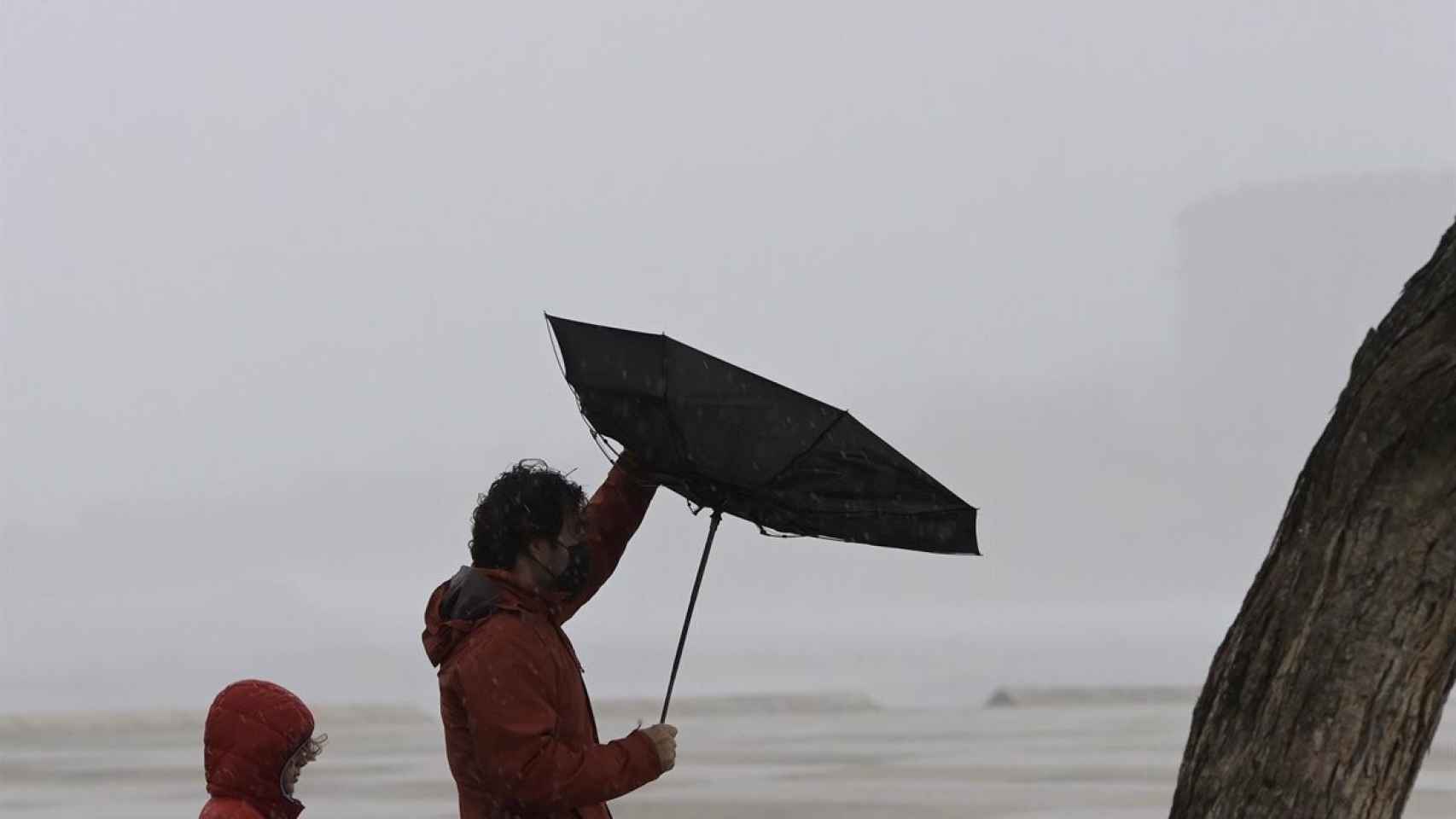 Un hombre tiene problemas con su paraguas por el viento