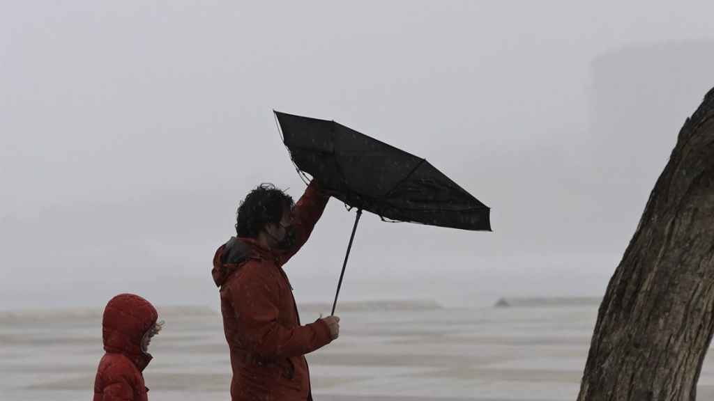 Un hombre tiene problemas con su paraguas por el viento