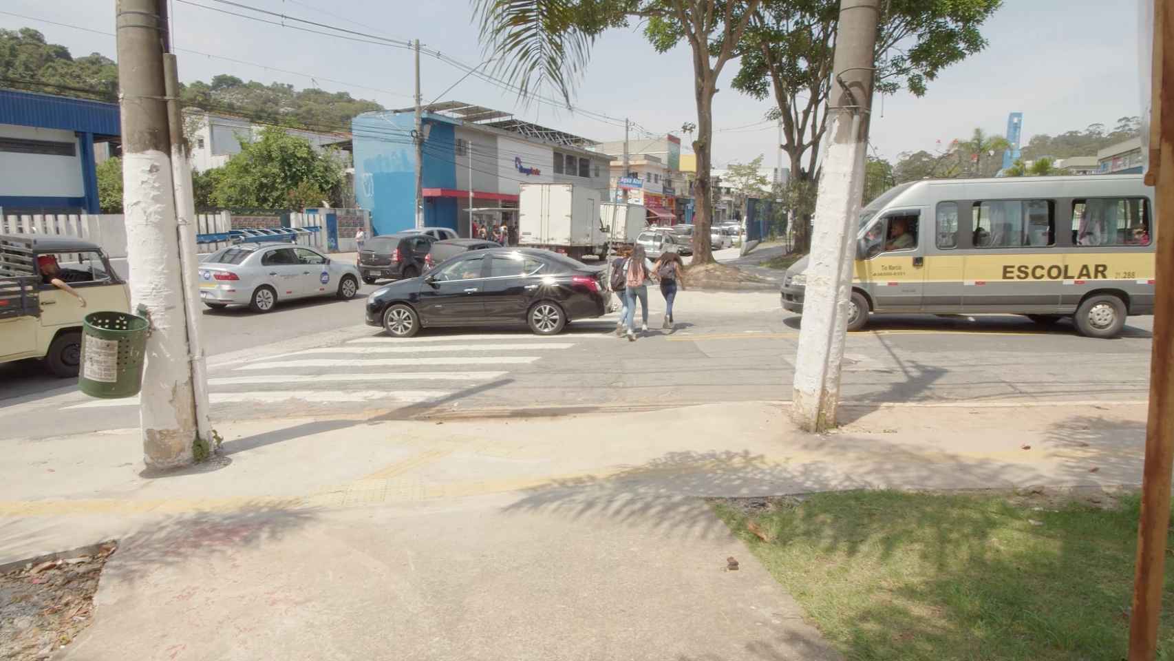 Un vehículo circula mientras unas niñas cruzan por el paso de peatones