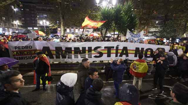 Decenas de personas portan una gran pancarta, durante una concentración contra la amnistía, frente a la sede del PSOE