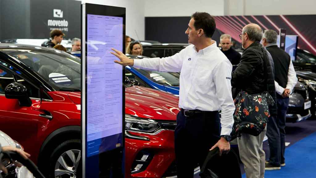 Un visitante repasa en un panel digital las características de un coche