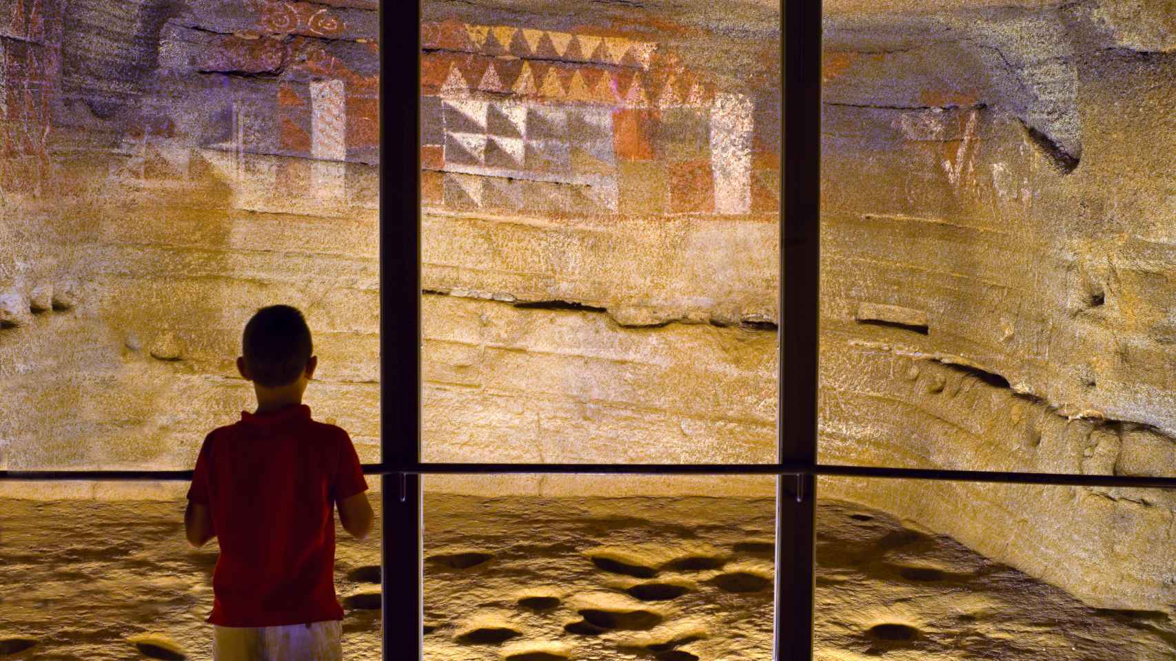 Un niño observa las pinturas del yacimiento arquológico de Cueva Pintada, en Gáldar