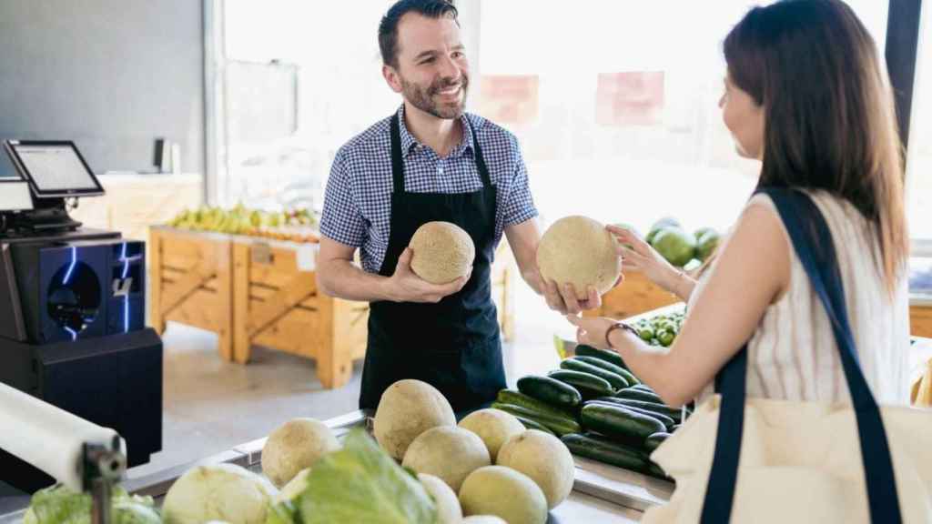 Un comerciante atiende a una clienta en su establecimiento