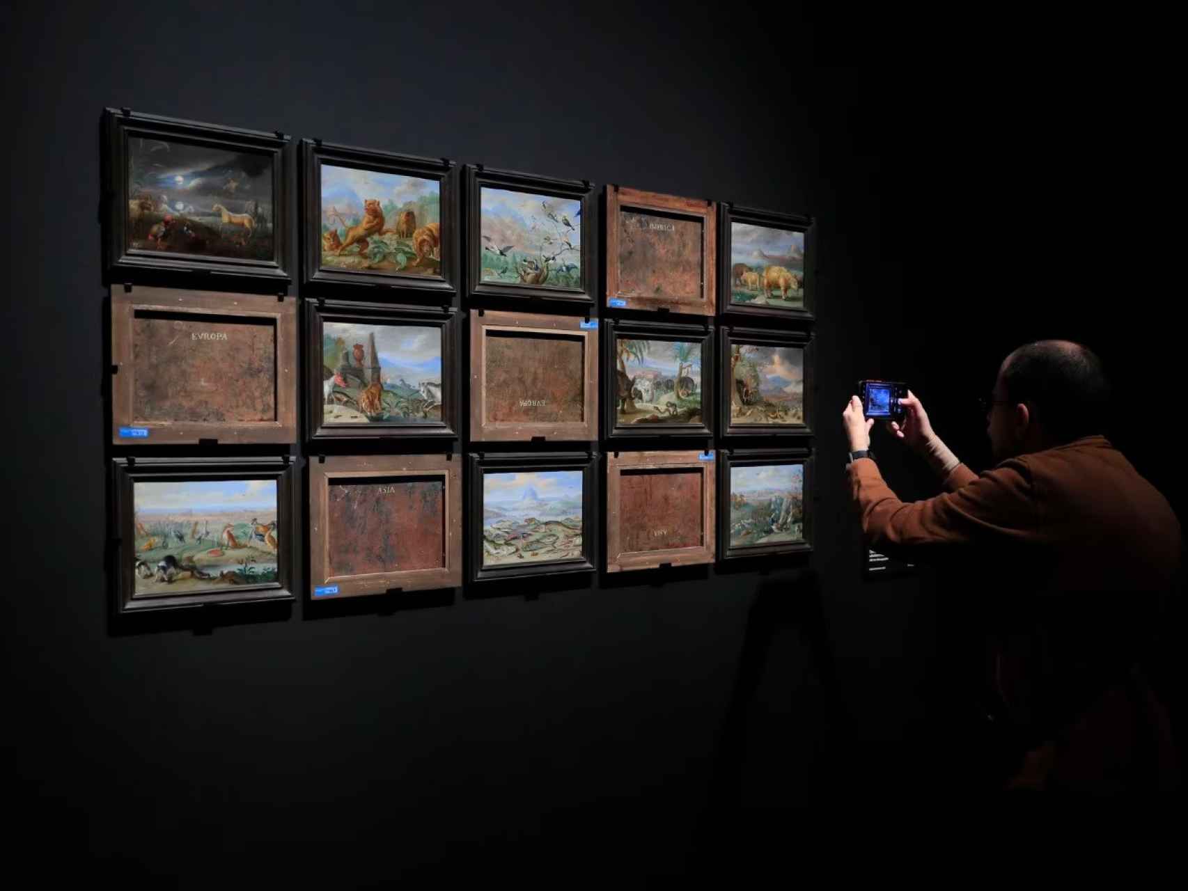Una persona toma fotografías de algunas de las obras expuestas por delante y por detrás en la exposición ‘Reversos’.