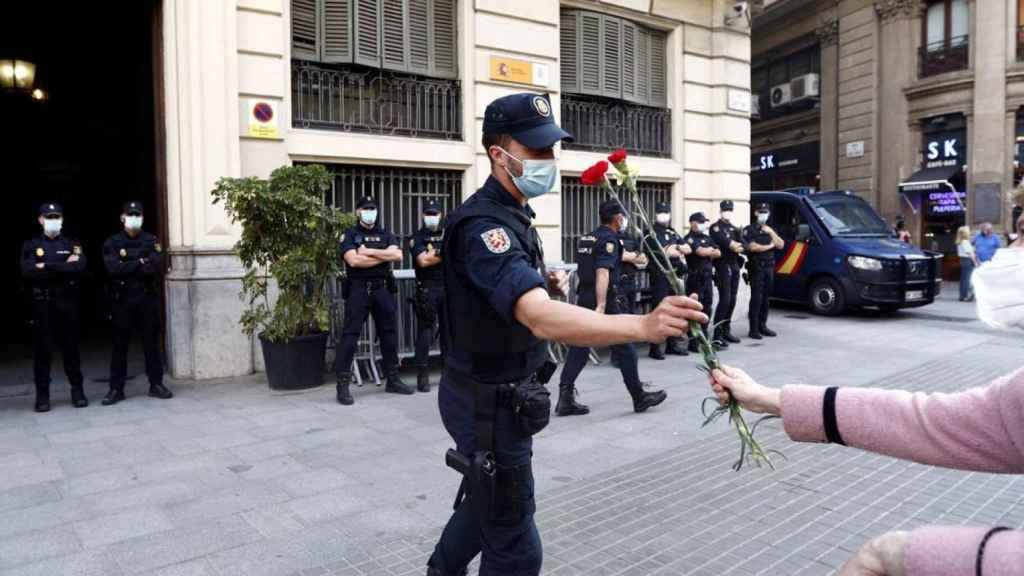 Una ciudadana da un clavel a un agente del CNP ante la Jefatura de Via Laietana